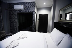 A hotel room with a neatly made bed, a large mirror, and a wall-mounted air conditioner. - Golden Star Pattaya (Pattaya)