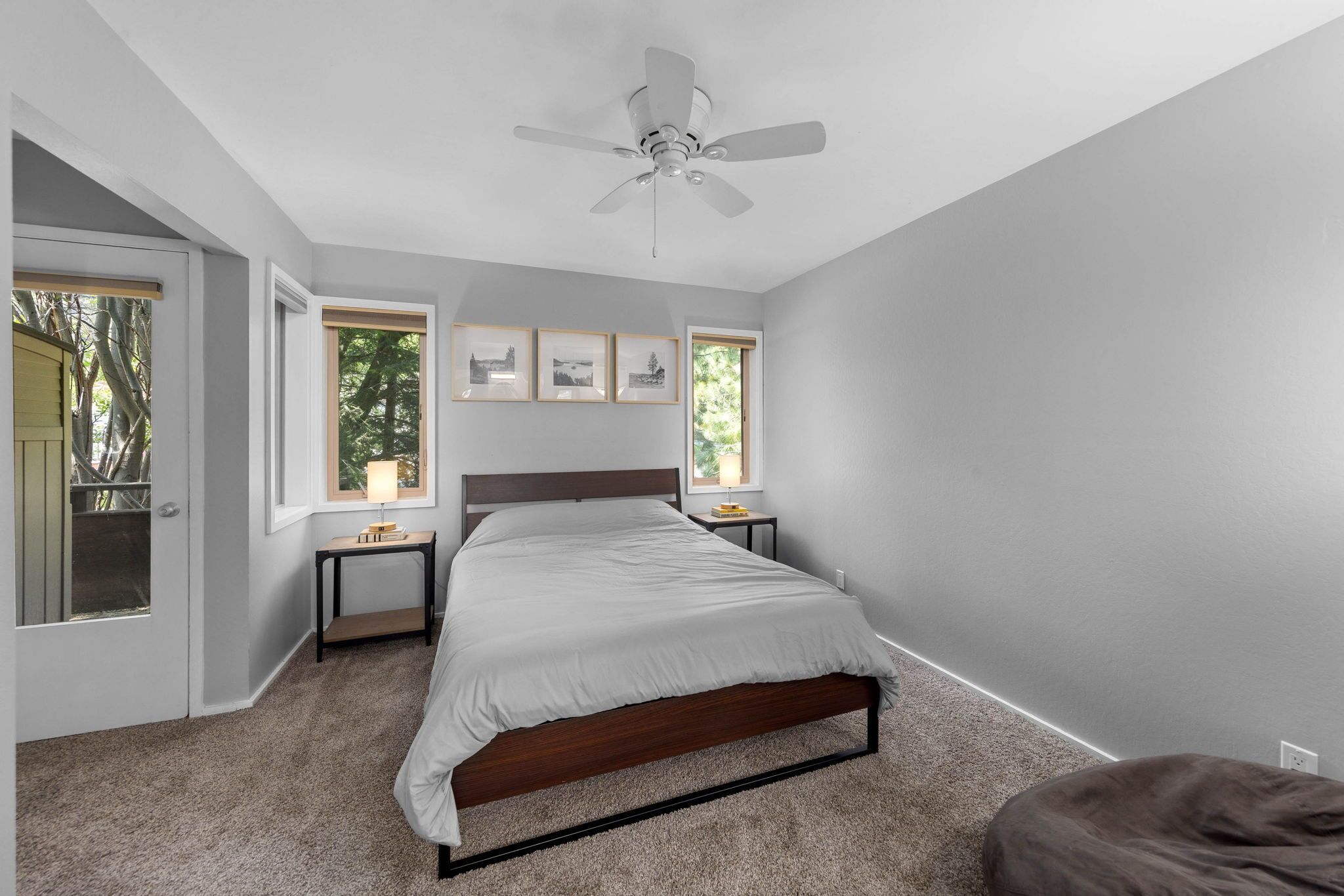 A bedroom with a bed, a ceiling fan, two bedside tables, and a window.