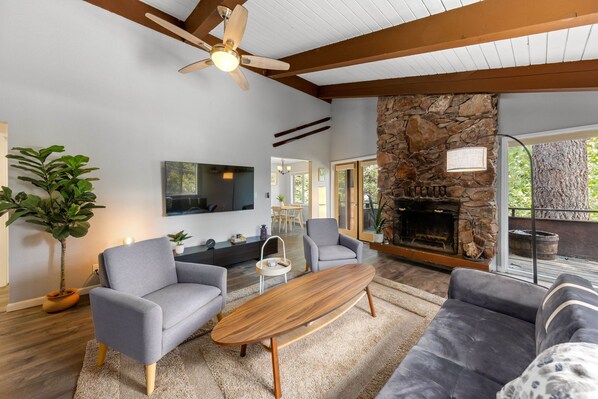 Una sala de estar moderna con chimenea de piedra, asientos cómodos y ventilador de techo.