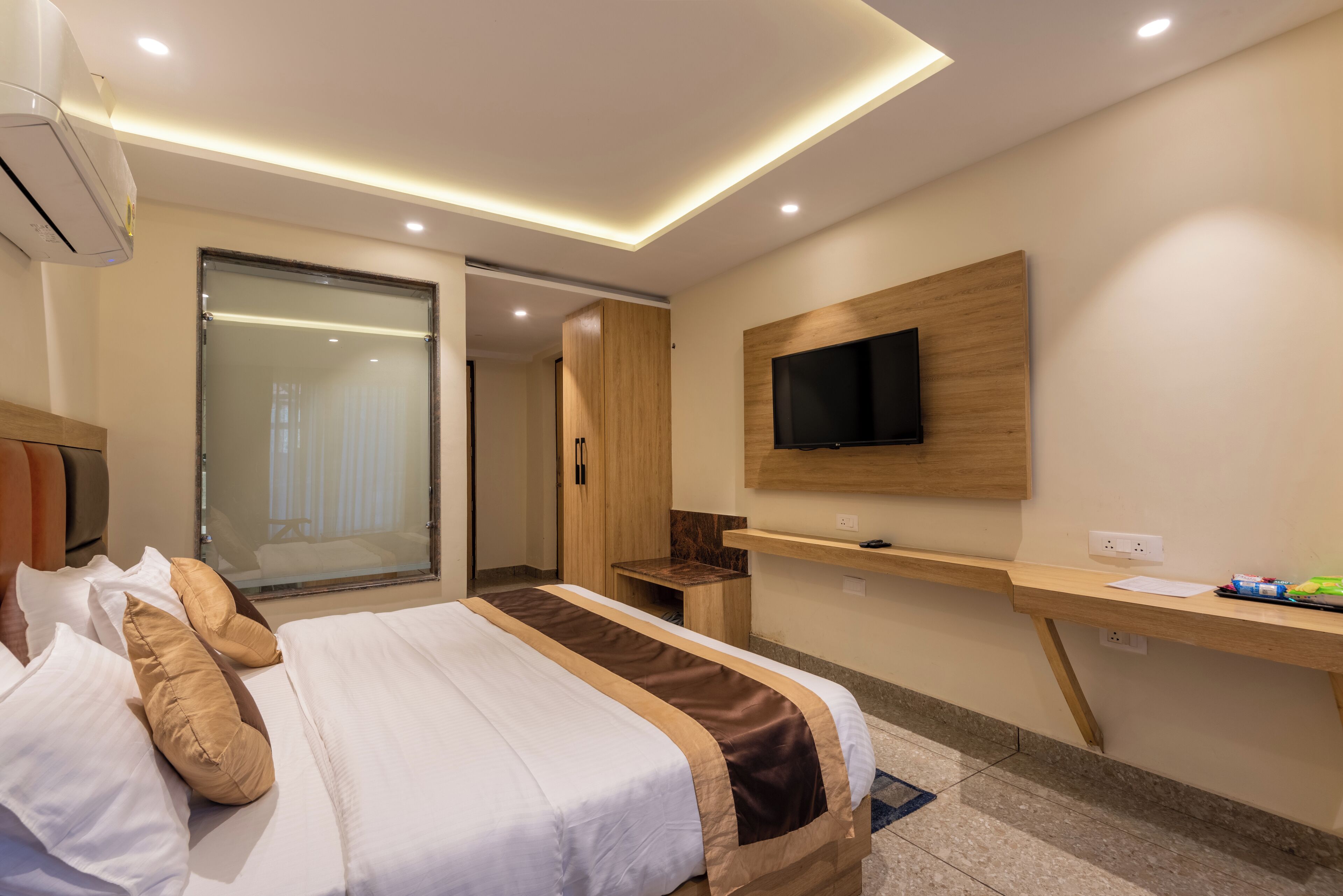 A hotel room with a bed, a desk, a TV, and a sliding door.