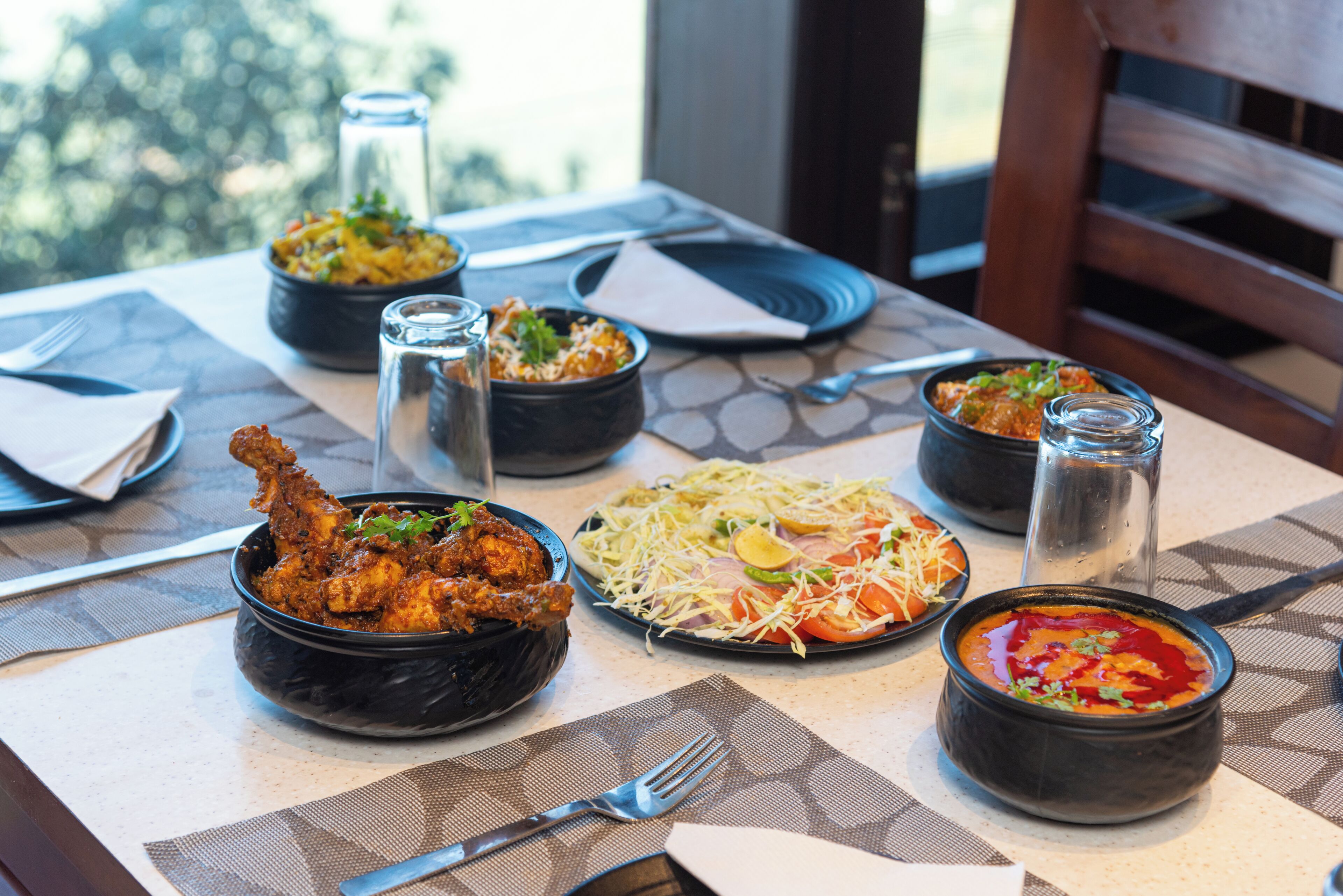 A table set with various dishes, including fried chicken, a salad, and a bowl of soup.