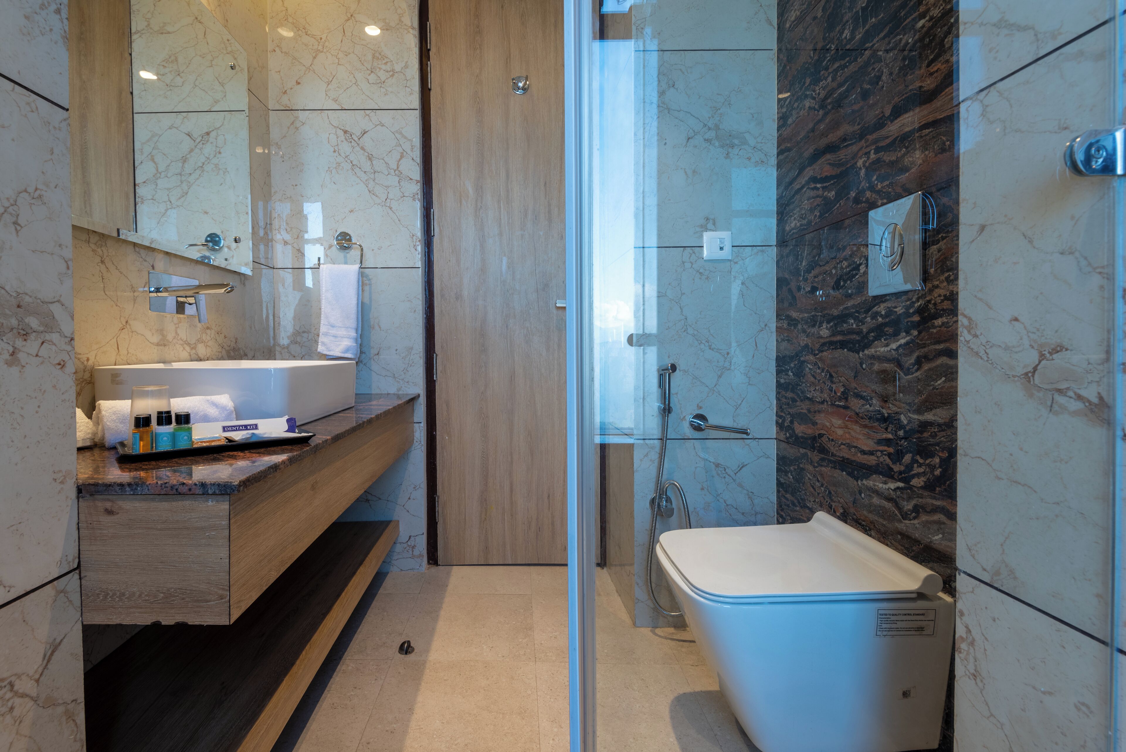 Une salle de bain moderne avec un meuble-lavabo en marbre, une baignoire et une douche séparée par une paroi en verre.