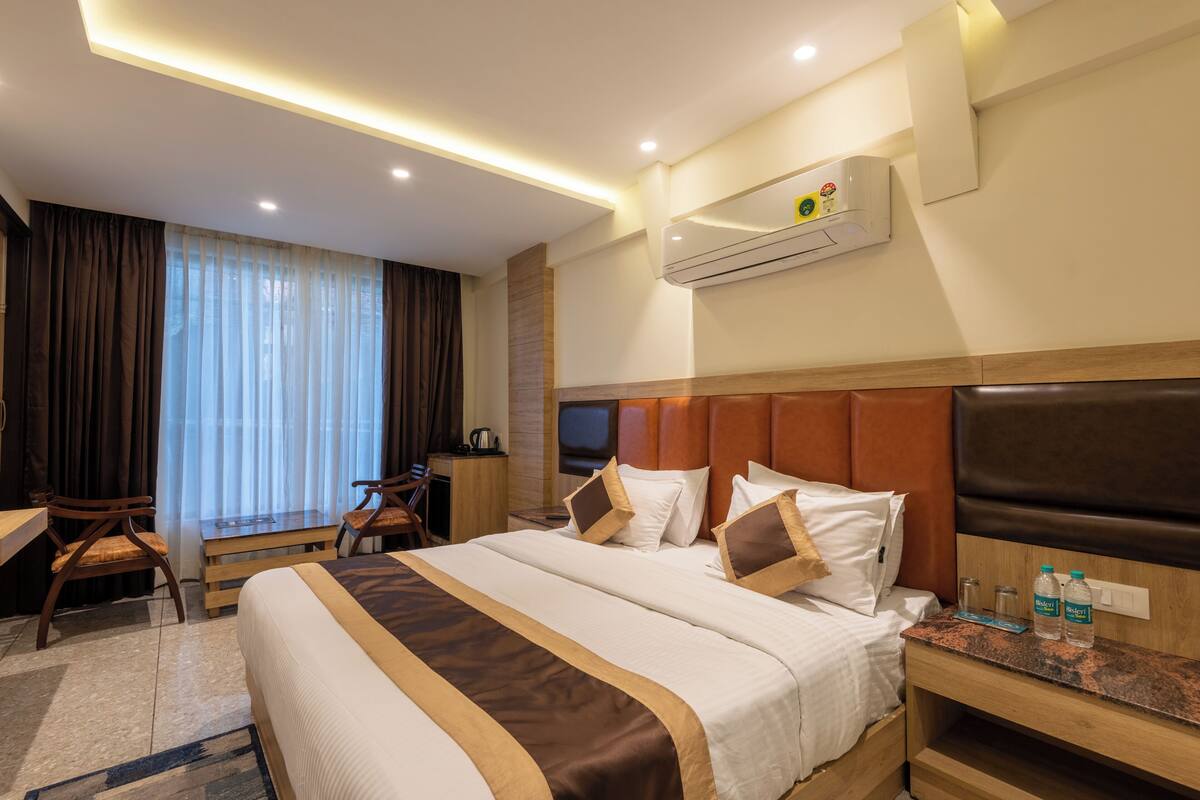 Habitación de hotel con una cama grande, un escritorio con silla, televisión y un equipo de aire acondicionado en la pared.