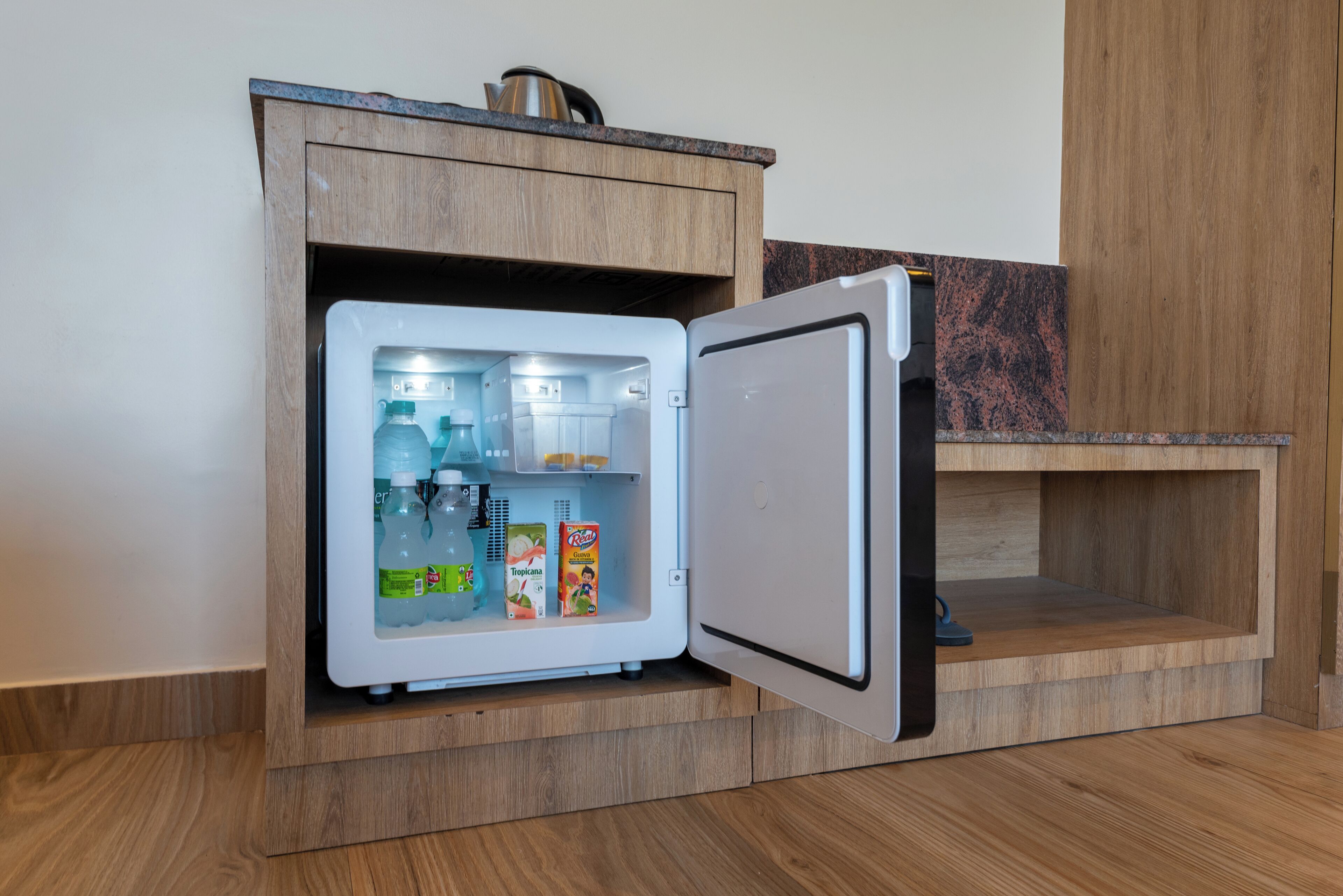 A compact refrigerator with a freezer compartment, built into a wooden cabinet with a countertop above.
