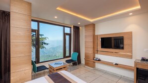 Una habitación de hotel moderna con un ventanal grande, una cama, un televisor y una mesita.