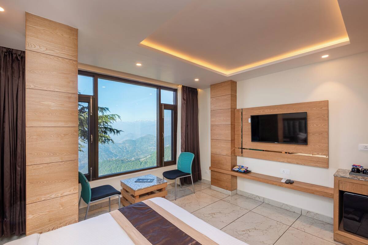 Una habitación de hotel moderna con un ventanal grande, una cama, un televisor y una mesita.