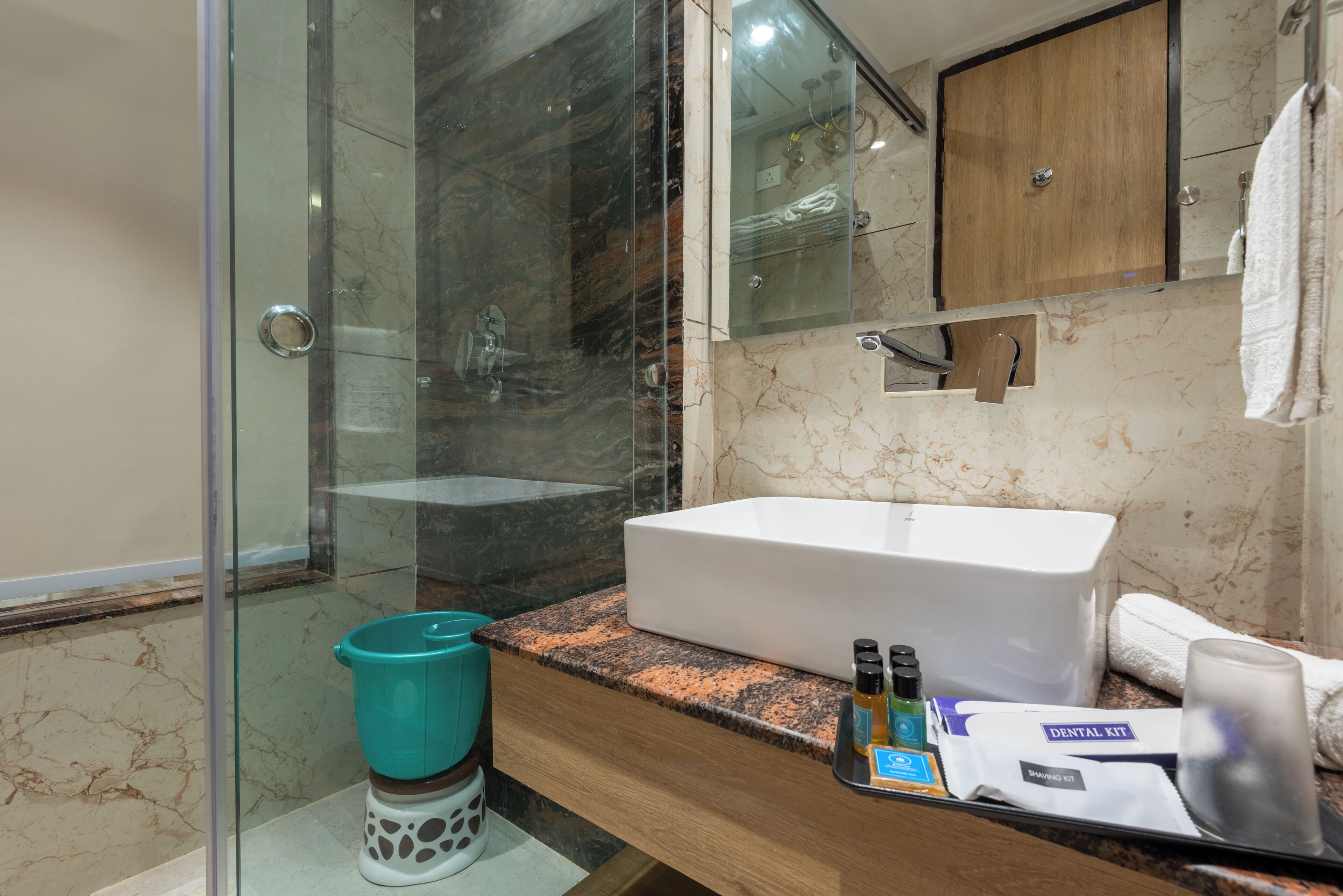 Un baño con cabina de ducha de vidrio, lavamanos blanco y tocador de madera.