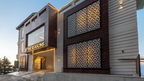 Un hotel moderno con una entrada destacada, amplias ventanas y una fachada decorativa.