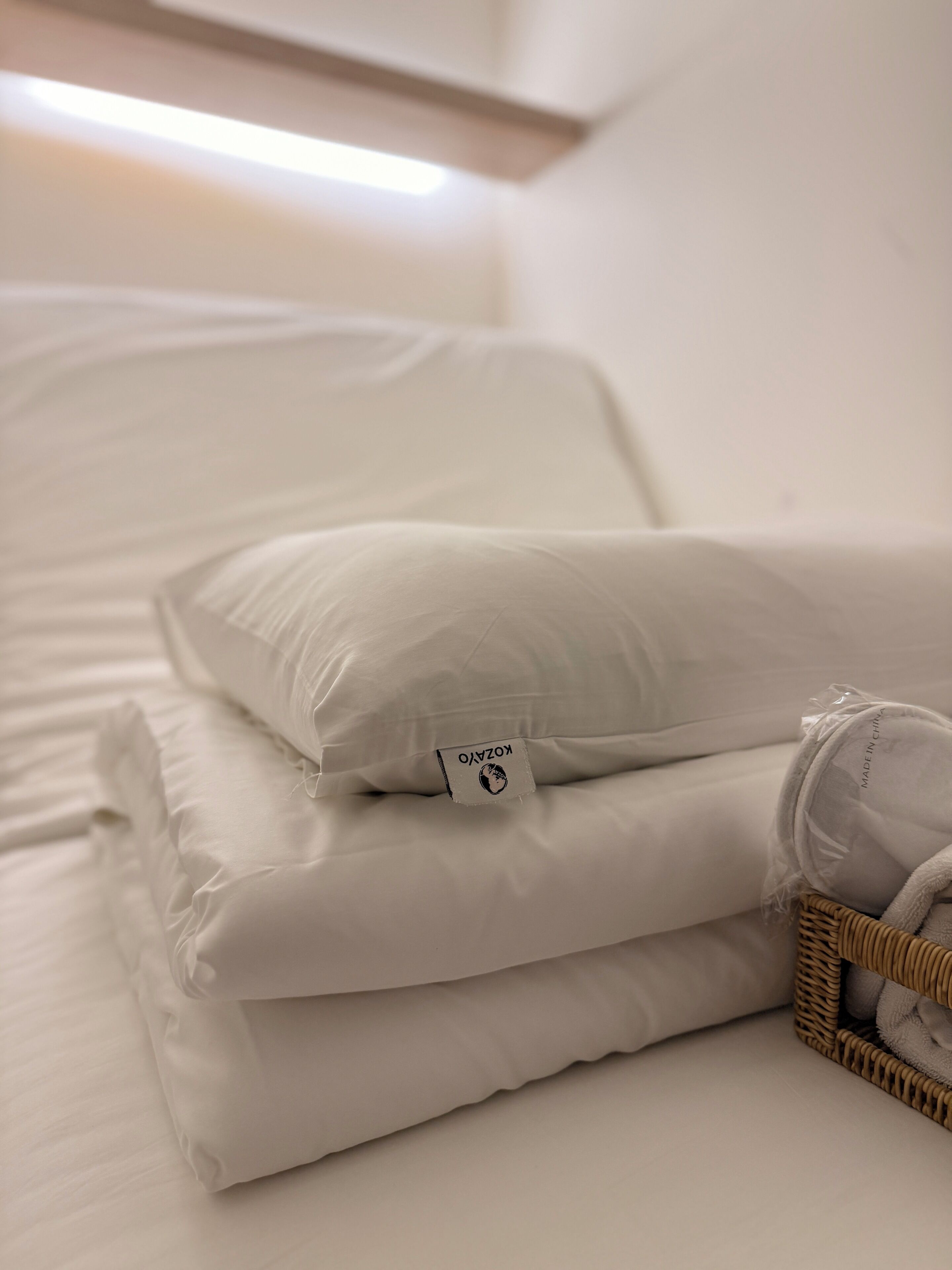 A neatly made bed with white bedding and a pillow with a visible brand tag.