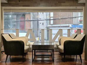 A modern interior with two chairs, a table, and a large window with a view of the city. - KOZAYO Hongdae Hostel (Seoul)