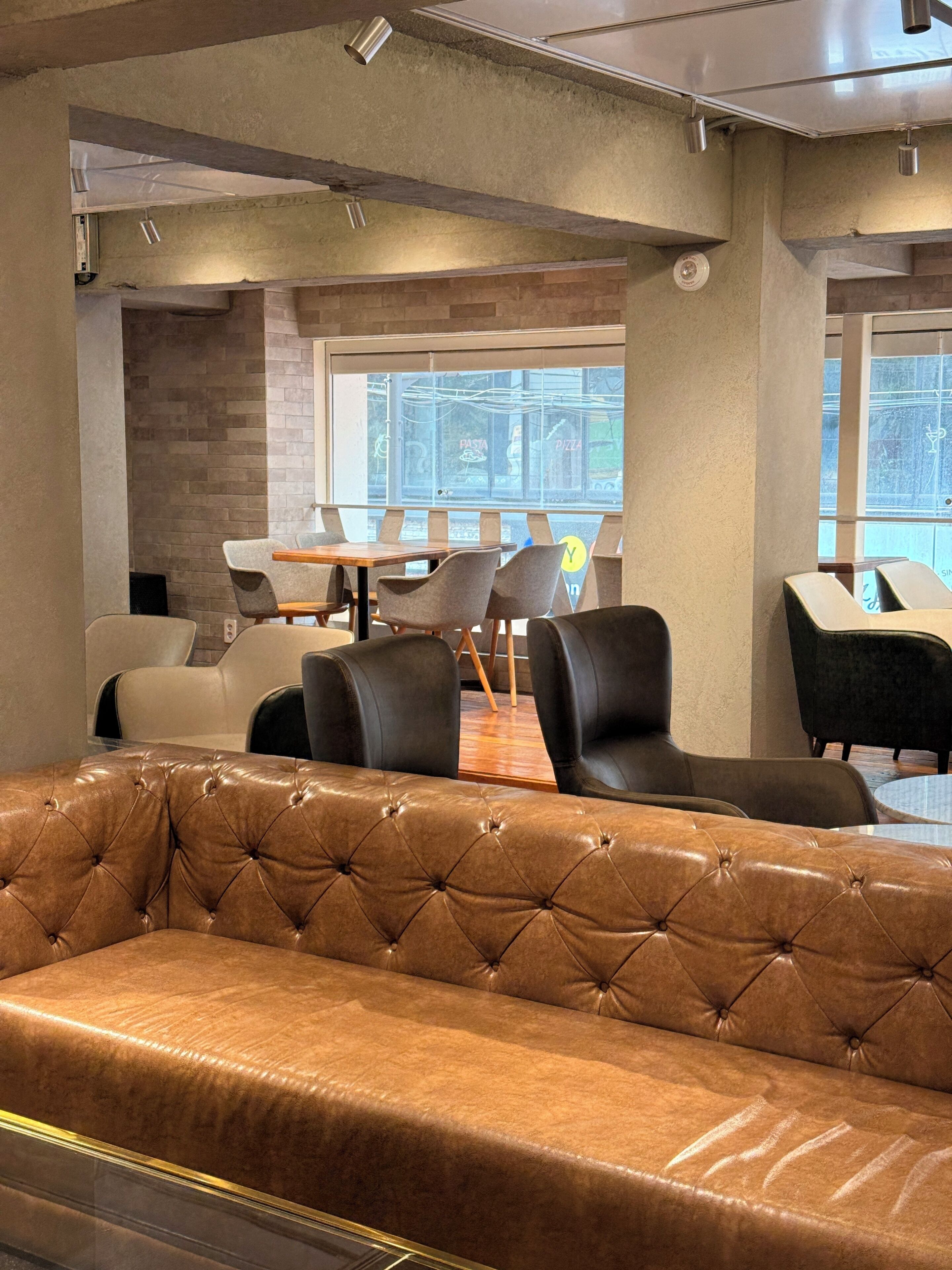 Een modern interieur met een leren bank, eethoek en grote ramen.