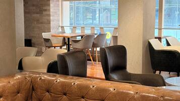 Een modern interieur met een leren bank, eethoek en grote ramen.