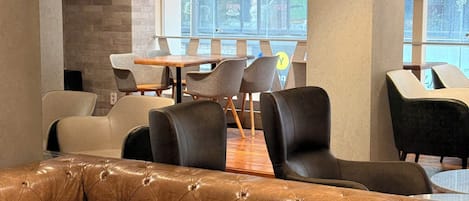 A modern interior with a leather sofa, dining area, and large windows.