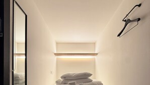 A small, narrow room with a bed, a bedside table, and a mirror. - KOZAYO Hongdae Hostel (Seoul)