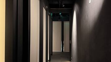 A corridor with a carpeted floor, black walls, and a door at the end.