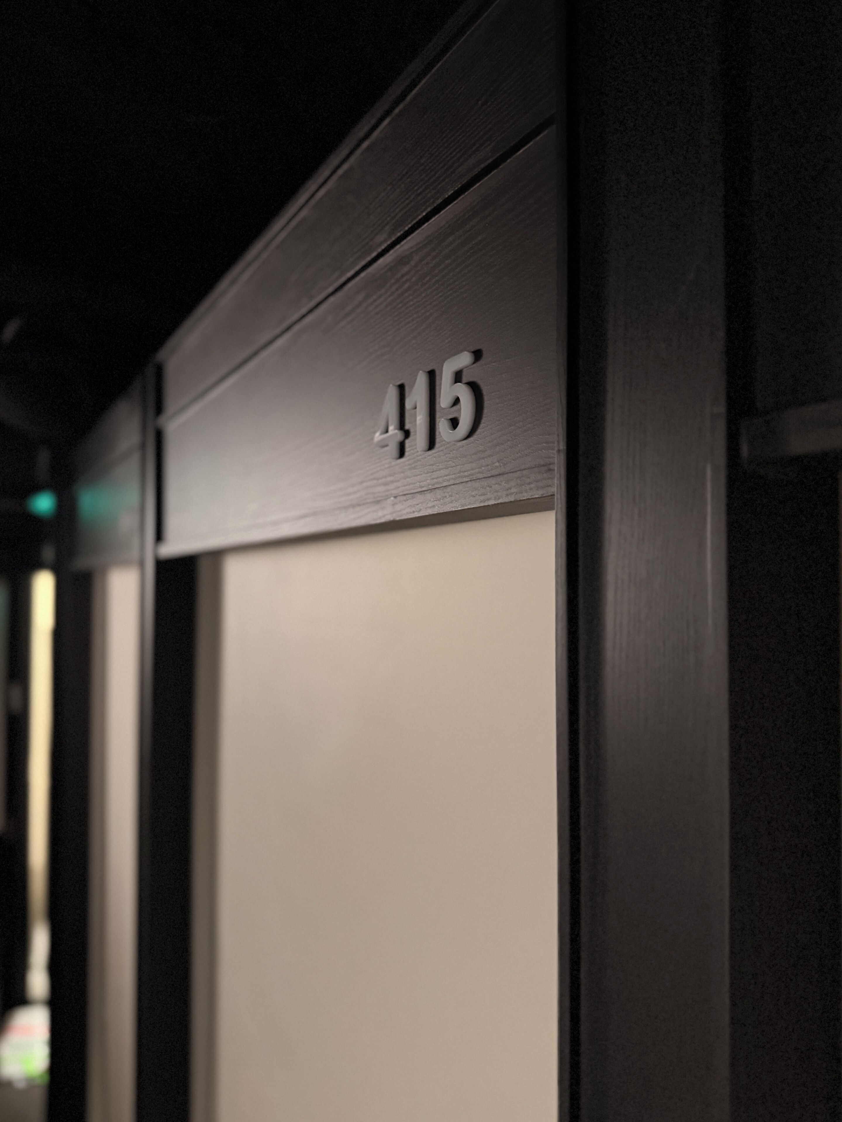A close-up of a dark wooden door with the number '415' indicating a room or location.