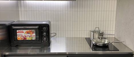 Una cocina con microondas, estufa y armarios.