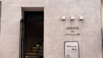 A building entrance with a sign for 'KOZAYO and millennials cafe' and a staircase leading inside.