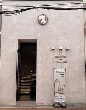 A building entrance with a sign for 'KOZAYO and millennials cafe' and a staircase leading inside. - KOZAYO Hongdae Hostel (Seoul)