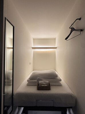 A compact room with a bed, a hanging light fixture, and a mirror. - KOZAYO Hongdae Hostel (Seoul)