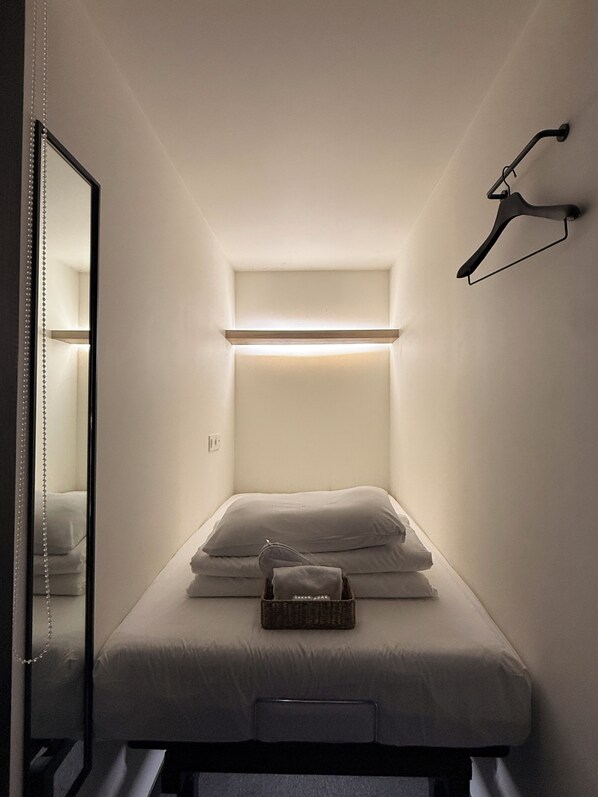 A compact room with a bed, a hanging light fixture, and a mirror. - KOZAYO Hongdae Hostel (Seoul)