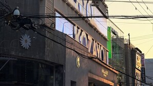 A building with a large sign that reads 'KOZANOV' and a smaller sign for 'OLIVE YOUNG' below it. - KOZAYO Hongdae Hostel (Seoul)