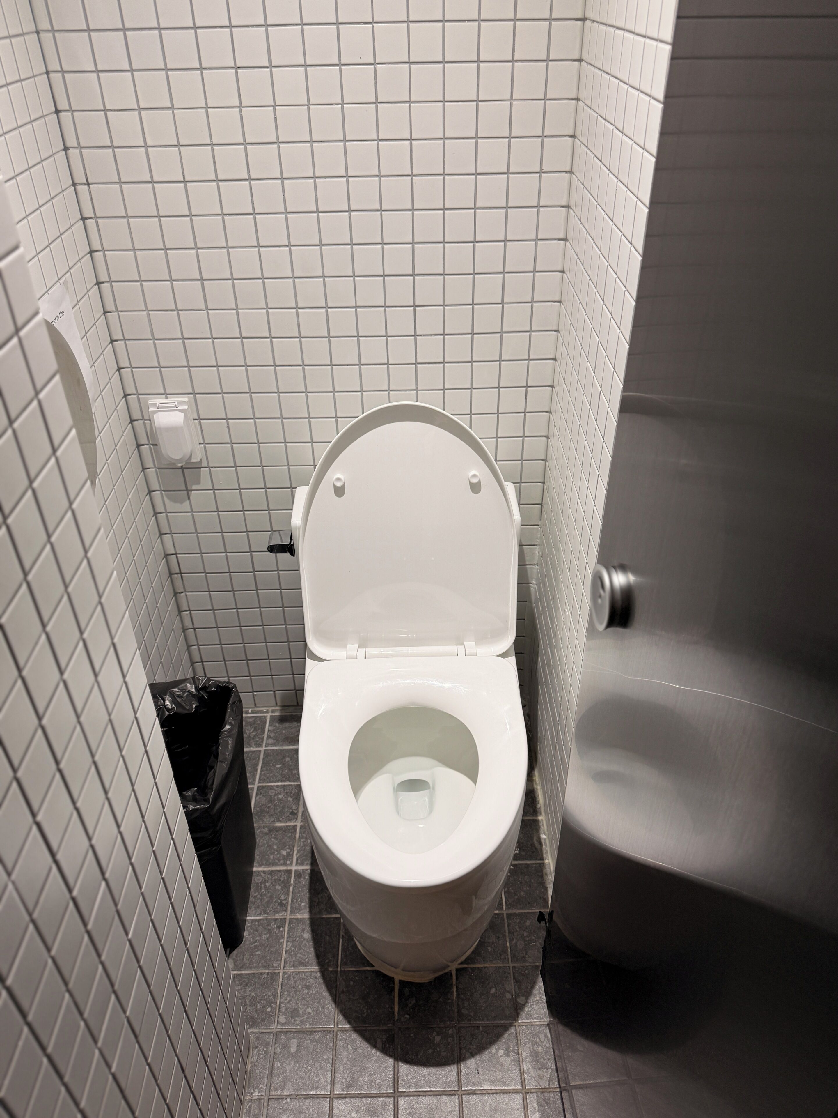 A white toilet with a closed lid in a tiled bathroom.