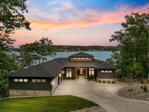 Stunning home with a glass door and windows, set amidst a beautifully manicured lawn and serene surroundings.
