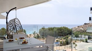 A balcony with a table set for breakfast, overlooking a coastal view. - ASTER sweet apartment (Villajoyosa)