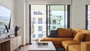 A modern living room with a sofa, coffee table, and a view of a building with balconies. - ASTER sweet apartment (Villajoyosa)