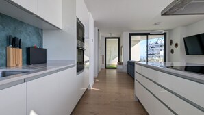 Eine moderne Küche mit weißen Schränken, Holzboden und Blick auf einen Balkon.