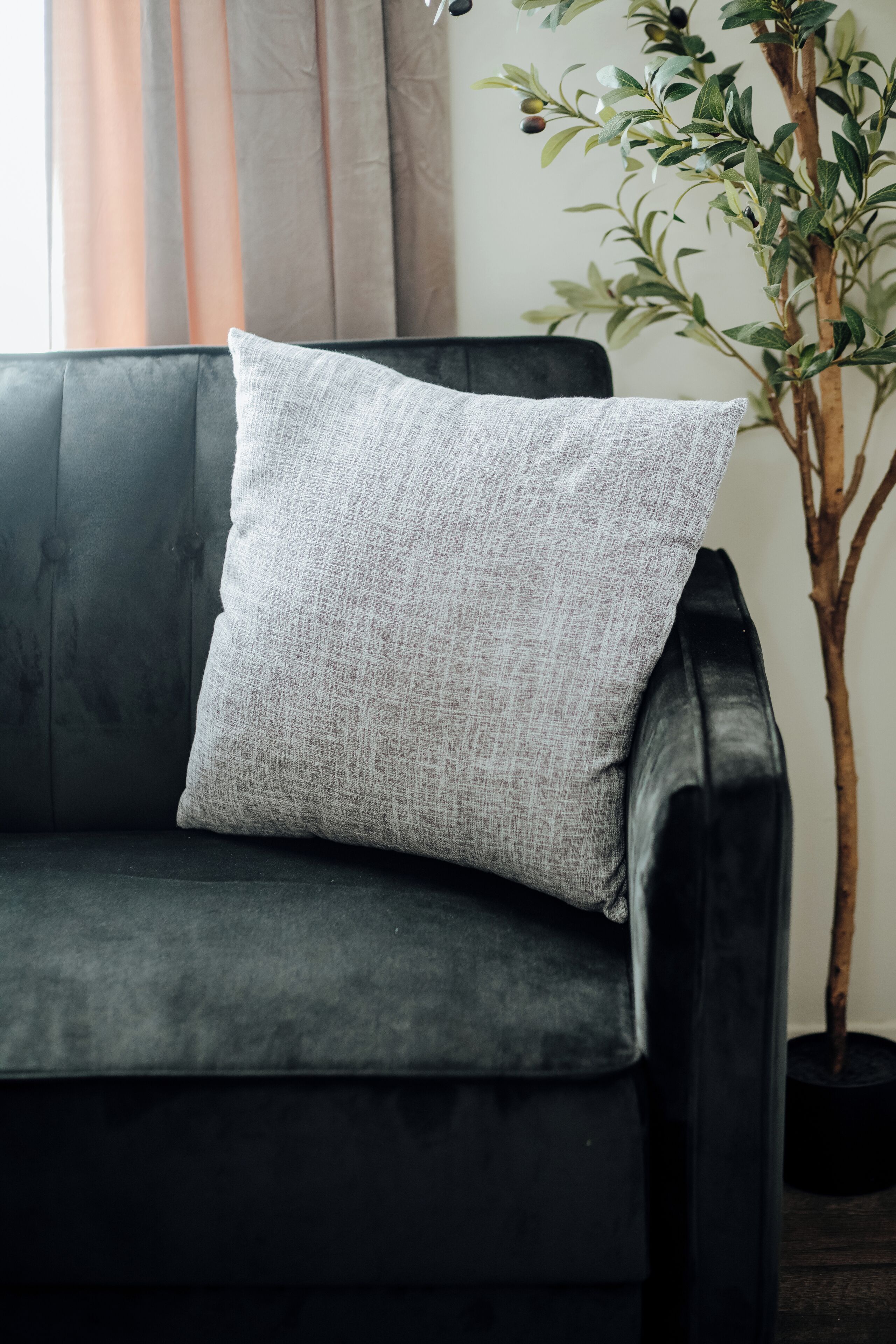 A dark-colored sofa with a textured grey pillow.