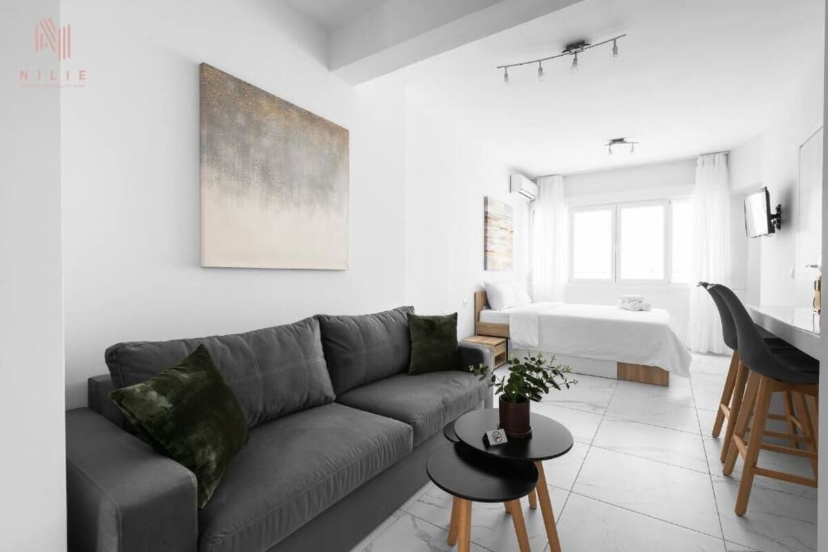 A modern, minimalist living room with a grey sofa, a small round table, and a painting on the wall.