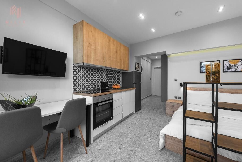 A compact kitchen with a TV, wooden cabinets, and a tiled backsplash.