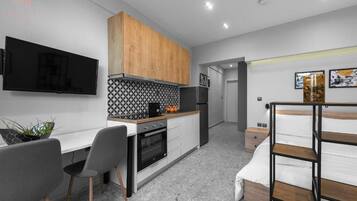 A compact kitchen with a TV, wooden cabinets, and a tiled backsplash.