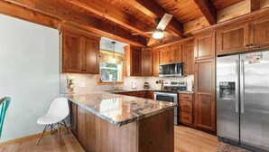 A kitchen with wooden cabinets, a stainless steel refrigerator, and a granite countertop island. - Branson's Crystal Cabin (Omaha)