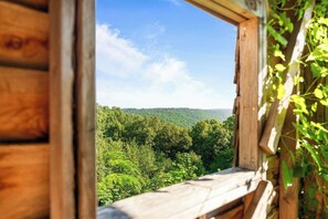Eine Holzhütte mit Blick auf einen bewaldeten Gebirgszug.