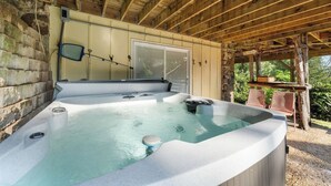 A hot tub under a wooden pergola with a stone wall and a window. - Branson's Crystal Cabin (Omaha)