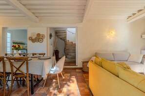 A dining area with a table set for four, a sofa, and a staircase leading to another level.
