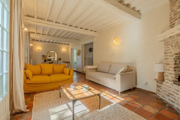 A living room with a yellow sofa, a white sofa, a coffee table, and a stone wall.