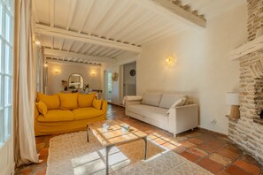 A living room with a yellow sofa, a white sofa, a coffee table, and a stone wall.
