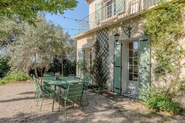A building with a balcony, a table with chairs, and a door.