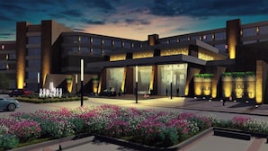 A modern hotel with a curved facade, large glass windows, and a well-lit entrance. - Tolip Resort El Galala Heights (Ataqah)