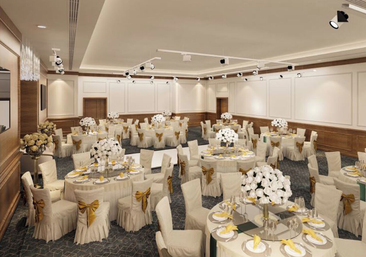 Un salón de banquetes con mesas redondas, sillas y centros de mesa florales.