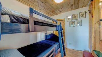 A bunk bed room with a wooden ceiling and a ladder.
