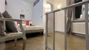 Un dormitorio con cama, una silla, un ventanal, un radiador y una puerta.