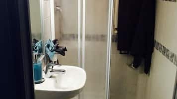 Uma casa de banho pequena com chuveiro, lavatório e sanita.