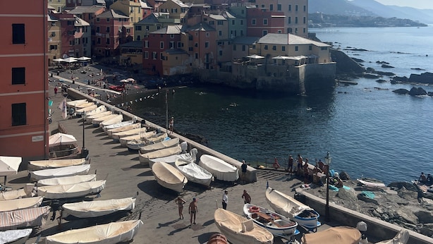 Un pueblo costero con edificios coloridos, un paseo marítimo y barcos amarrados al muelle.