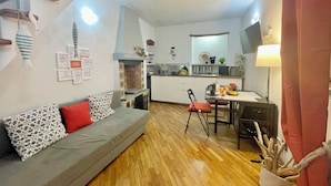 Un espacio habitable compacto con kitchenette, comedor y sofá con cojines estampados.
