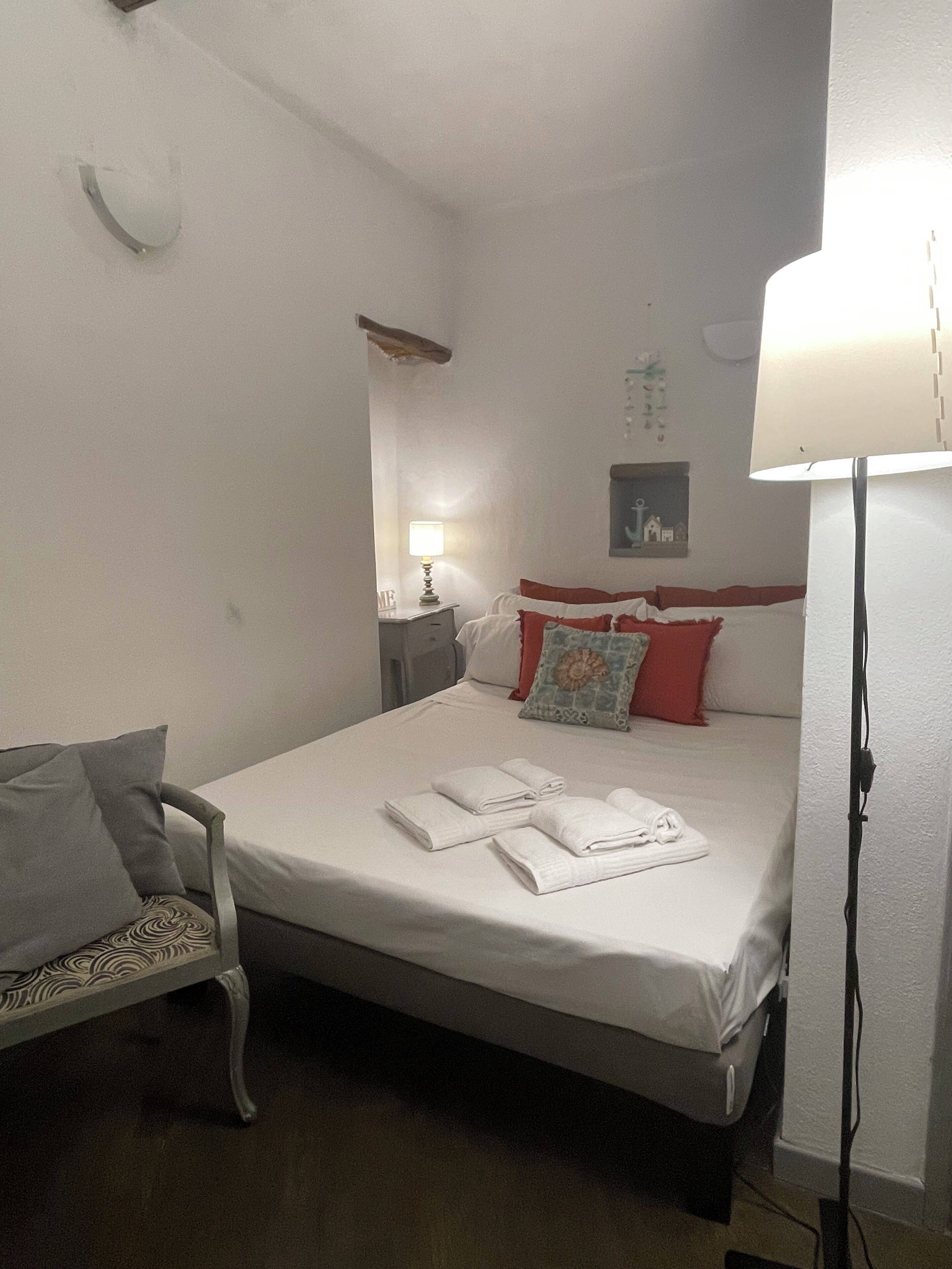 Una habitación de hotel con una cama individual, una silla, una mesita de noche y una lámpara.